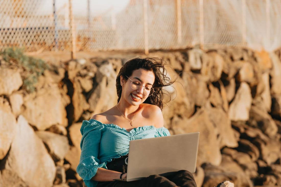 Mujer sonriente trabaja con su computadora portátil al aire libre.
